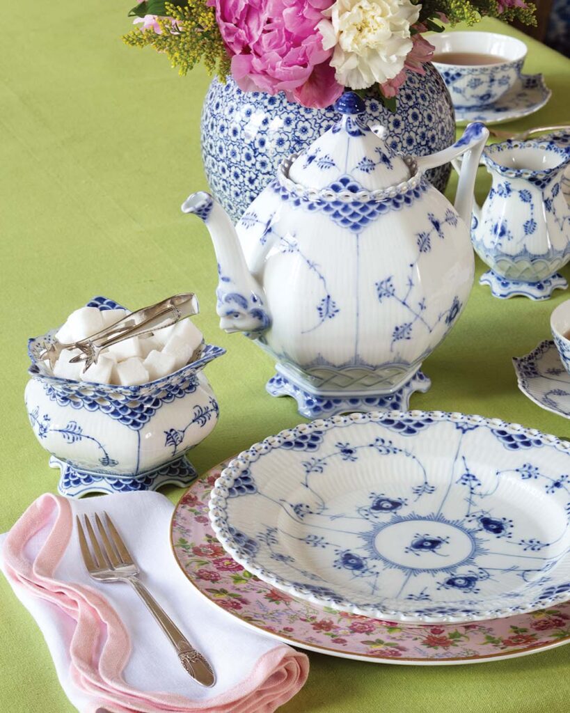 Pair Royal Copenhagen’s Blue Fluted Full Lace teapot, teacups, creamer and sugar set, and dessert plates with Royale Garden’s pretty Chintz Collection dinner plates and white napkins with pink scalloped trim. Add a pop of color to the table with a green tablecloth and finish the look with silver First Love flatware from Rogers Bros.