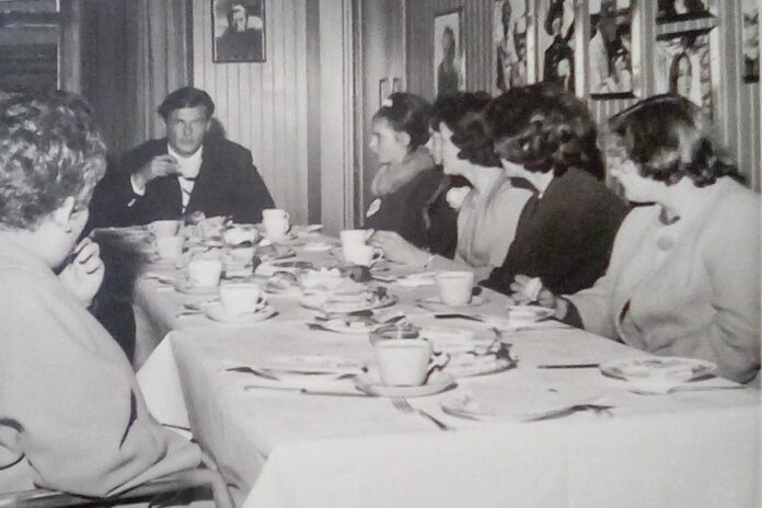 Vida and other young ladies excitedly enjoy afternoon tea with English actor Roger Moore at Elstree Studios.